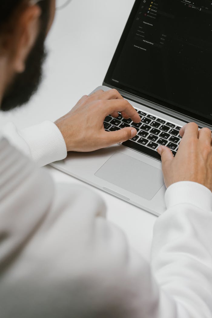pexels-photo-5474282 A male programmer intensely typing code on a laptop, showcasing modern technology and software development.
